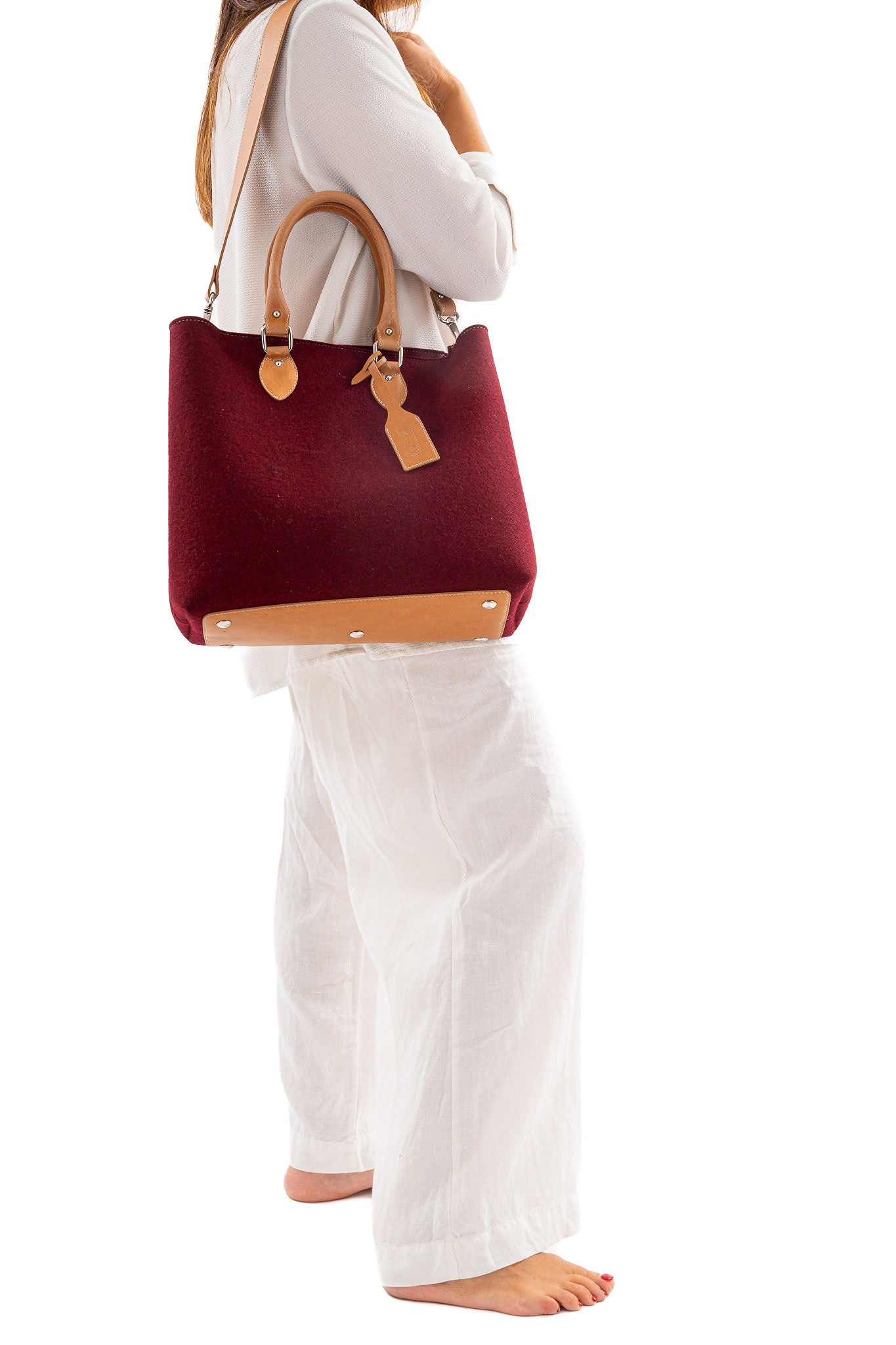 Merino wool felt in 3mm thickness. Vegan leather handles made from organic materials. Detachable Vegan leather shoulder strap with snap hooks. 2 inside pockets. Measurements approx.: 30cm H 33cm W 15cm D/ 11,81 H 12,99” W 5,90” D. Handles drop: 14,5 cm / 5,70”. Pendant plate with Lefrac logo.