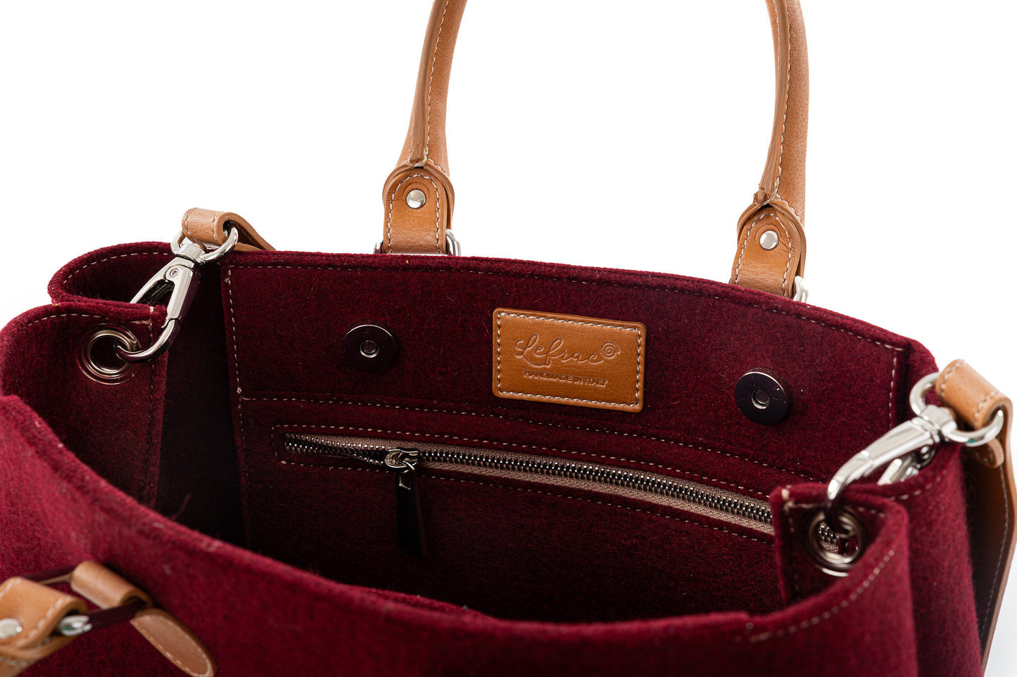 Merino wool felt in 3mm thickness. Vegan leather handles made from organic materials. Detachable Vegan leather shoulder strap with snap hooks. 2 inside pockets. Measurements approx.: 30cm H 33cm W 15cm D/ 11,81 H 12,99” W 5,90” D. Handles drop: 14,5 cm / 5,70”. Pendant plate with Lefrac logo.