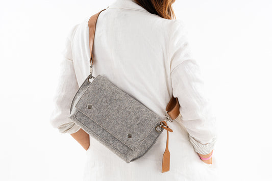 **Alt Text:**  "GREGOR Charcoal Grey Beltbag: Compact yet spacious, made from 3mm merino wool felt with a crossbody vegan leather strap. Features two external pockets for large phones, a smaller internal pocket, and a secure flap with magnetic buttons. Adjustable strap for versatile wear. Handmade in Italy. Includes dust bag."