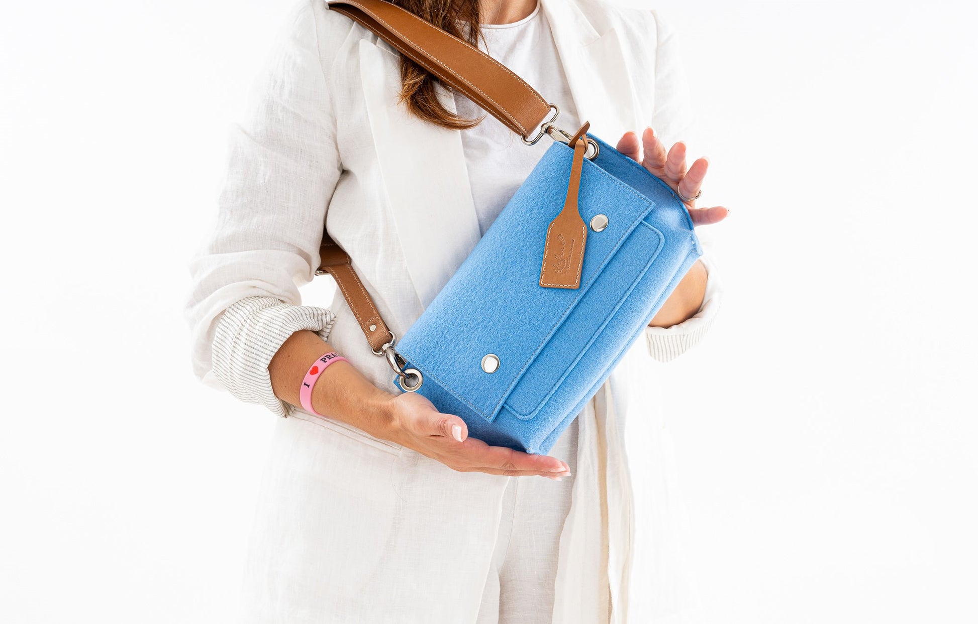 GREGOR Light Blue Beltbag: Compact yet spacious, made from durable 3mm merino wool felt with vegan leather. Features two external pockets for large phones, a smaller internal pocket, and a secure flap with magnetic buttons. Adjustable strap for versatile wear. Handmade in Italy. Includes dust bag. - Lefrac