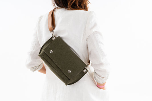 GREGOR Moss Green Beltbag: Compact yet roomy, made from 3mm merino wool felt with vegan leather. Features two external pockets for large phones, a small internal pocket, and a secure flap with magnetic buttons. Versatile with an adjustable strap for various wear options. Handmade in Italy and includes a dust bag. - Lefrac