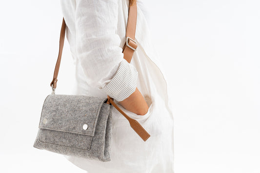 JOY Grey Crossbody Bag: Compact, ergonomic, and stylish with three pockets (2 external, 1 internal) for essentials. Features an adjustable vegan leather strap, flap with magnetic buttons, and a Lefrac logo pendant. Handmade in Italy, comes with a dust bag.