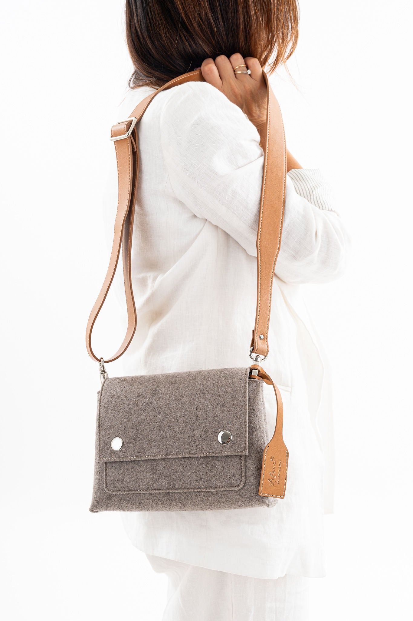JOY Taupe Crossbody Bag, crafted from 3mm Merino wool felt and bio-based vegan leather. Features three pockets (2 external, 1 internal), flap closure with magnetic buttons, and an adjustable strap. Handmade in Italy with durability and eco-friendly qualities. Comes with a dust bag.